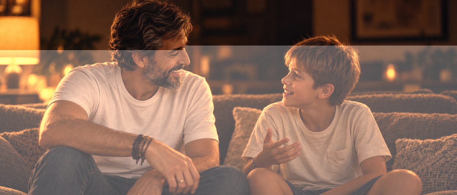 Padre e hijo conversando sonrientes en el sofá de casa